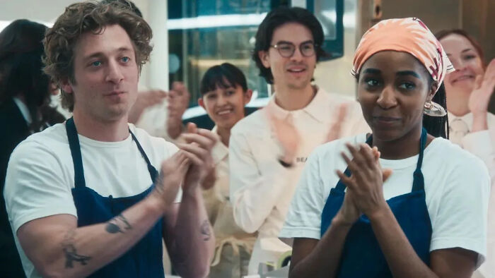 The Bear cast, including Carmy, applauding; showing a chaotic scene.