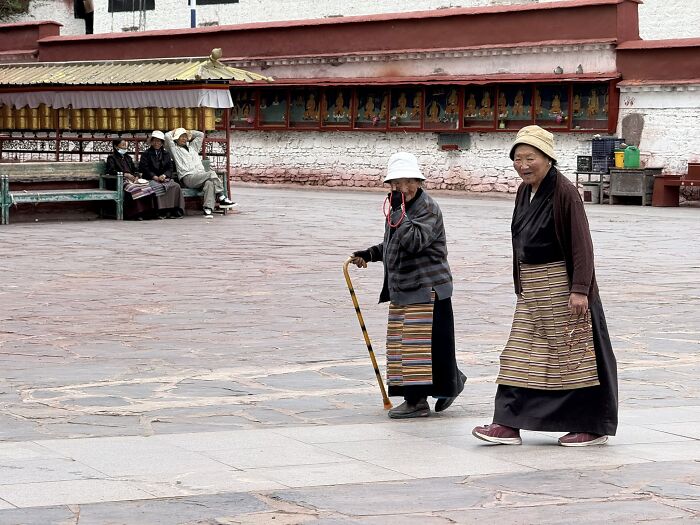 Two elderly women walking, one with a cane, in a courtyard in China, where a traveler found unique experiences.