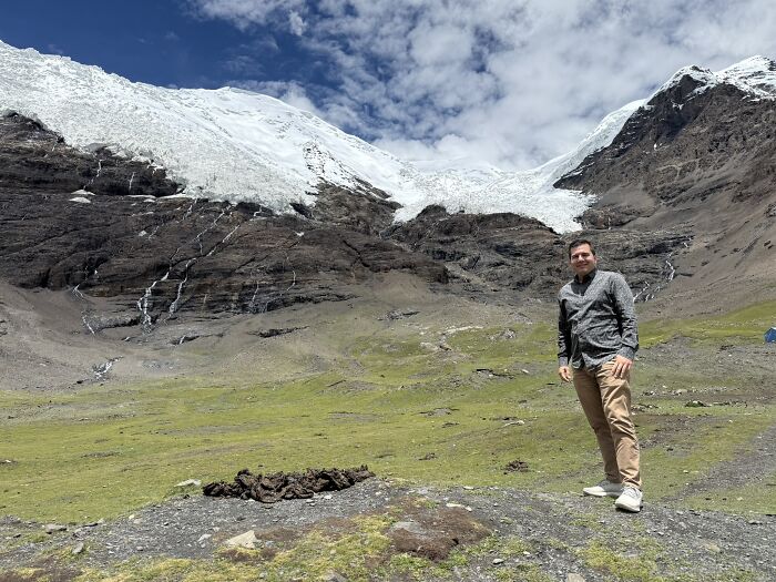Traveler posing in front of a stunning glacier in China, showcasing the country's diverse landscapes.