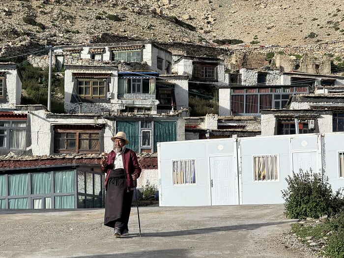 An elderly traveler walking through a village in China, reflecting the unique culture and architecture.