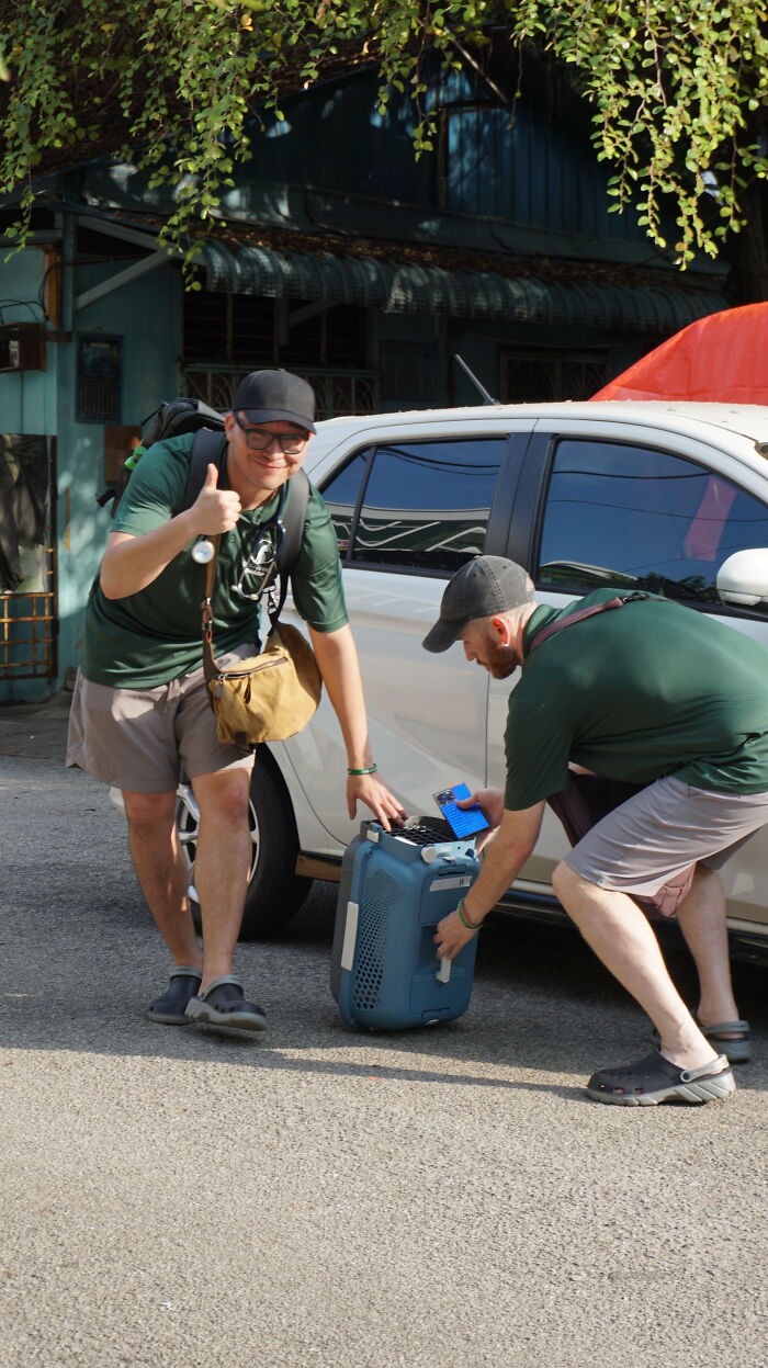 Two organization members using local action and clever technology to help street cats, carrying a cat carrier.
