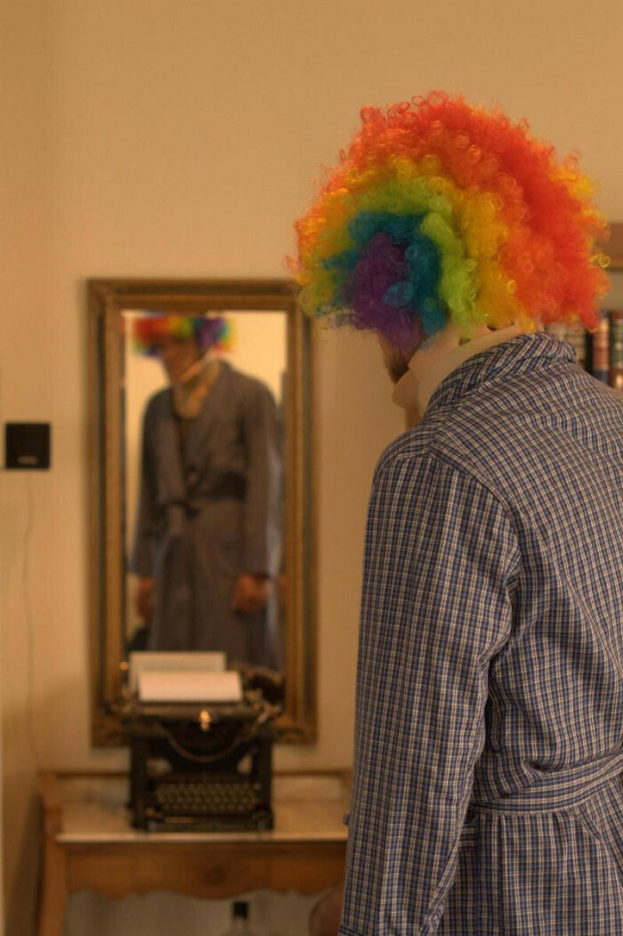 Person in rainbow clown wig facing mirror in creepy photo