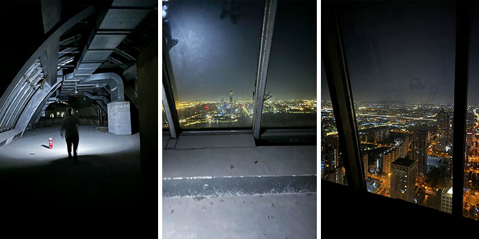 Urban exploration inside dark building with flashlight and city skyline views through windows