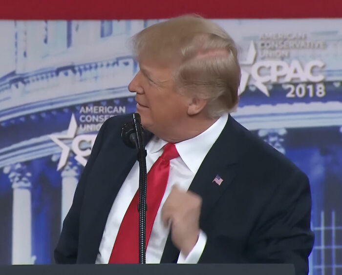 Donald Trump speaking at a podium, hair visible, relating to hair-loss treatment