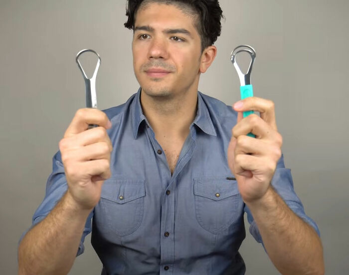Man holding two tongue scrapers in hands demonstrating oral hygiene tool