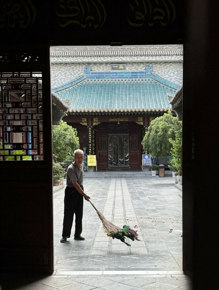 A man sweeping the courtyard of an ancient mosque in China, revealing the country's rich historical tapestry.