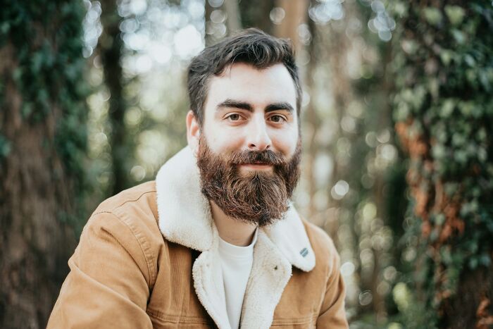 Bearded man in brown jacket in forest setting