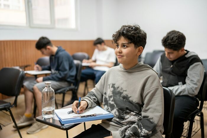 Gen Alpha student taking notes attentively in classroom setting