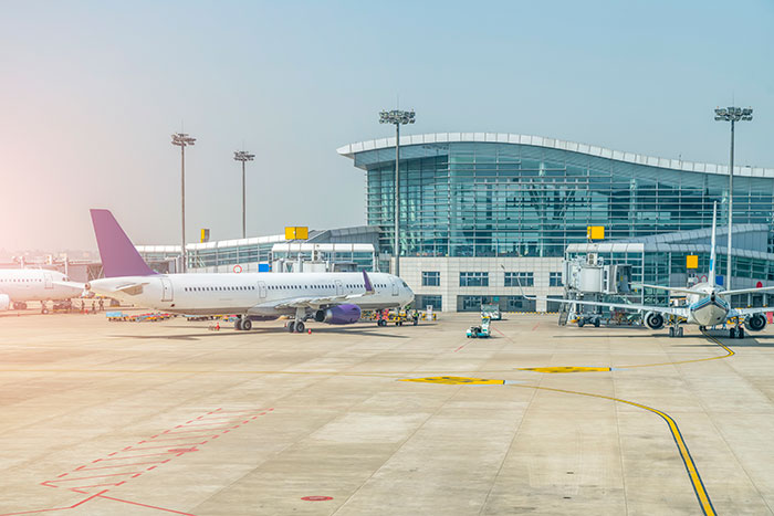 Airplanes parked at airport terminal on sunny day with modern airport building Airplanes parked at airport terminal on sunny day with modern airport building