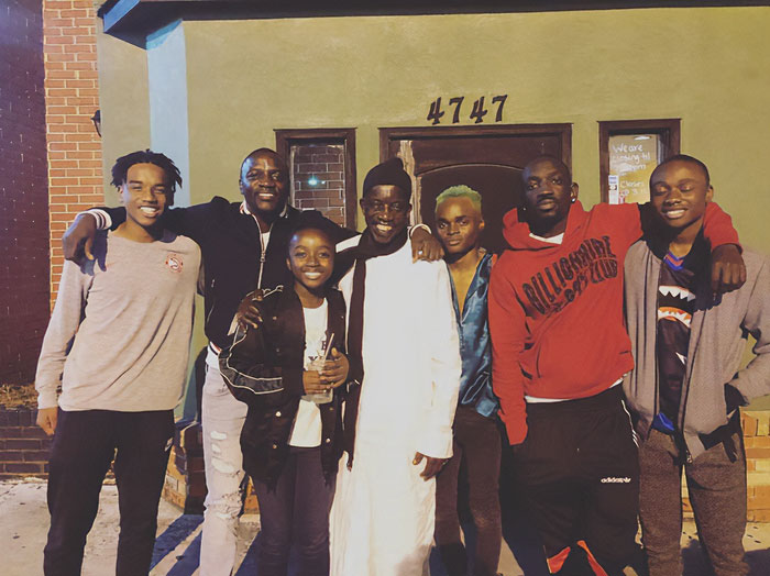 Akon standing with friends or family outside a building at night