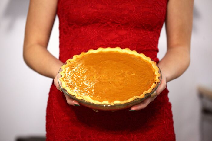 Woman in red dress holding a freshly baked pumpkin pie