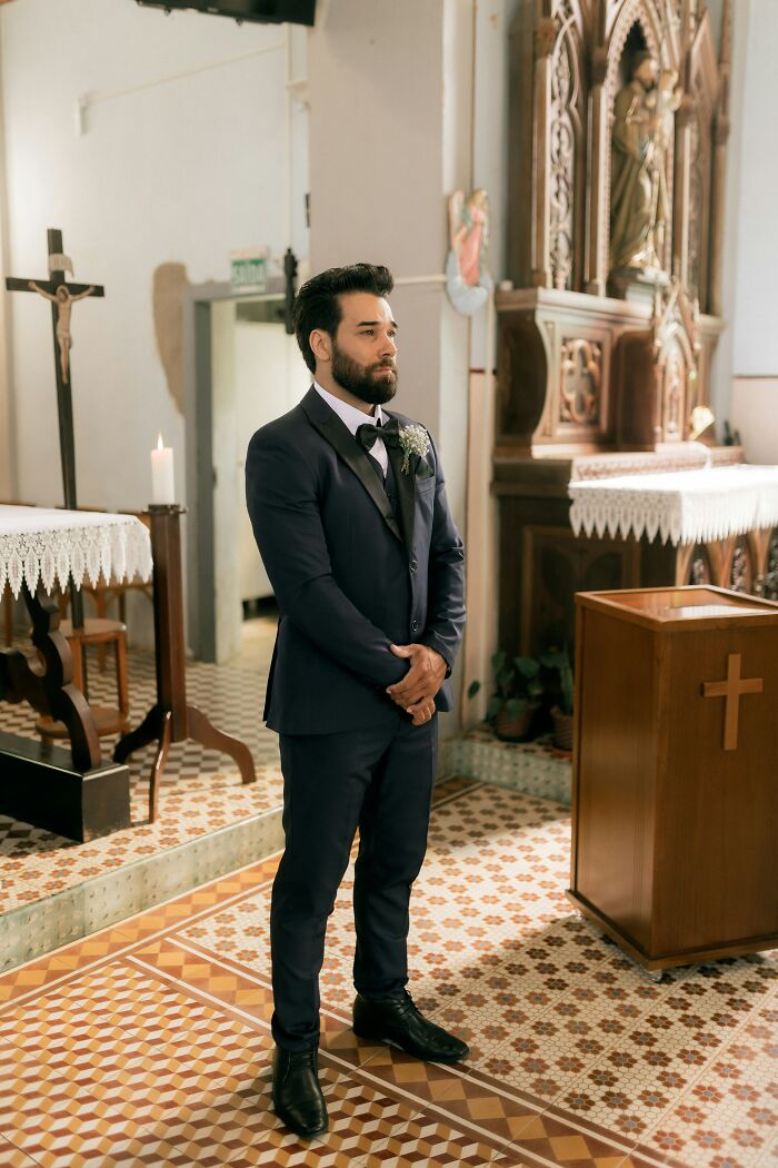 Groom in suit standing inside church during wedding