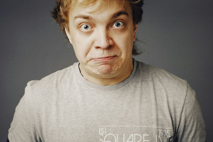Young man making a skeptical face in gray shirt