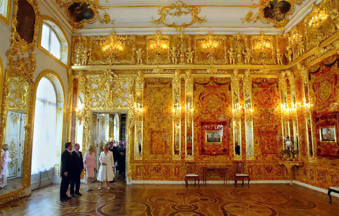 The restored Amber Room, a breathtaking chamber showcasing the brilliance of this lost treasure, with visitors admiring its golden splendor.