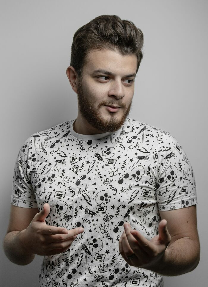 Man in skull print shirt gesturing while talking against gray background