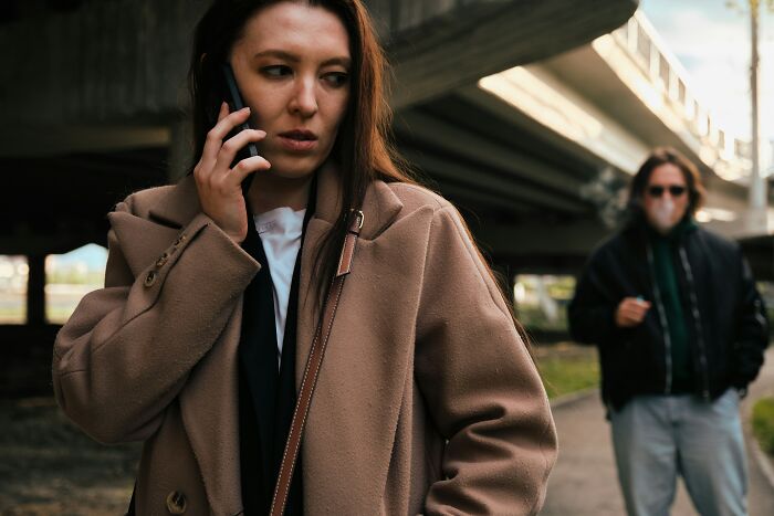 Woman on phone looking worried with man following under bridge unsettling thing found about friend