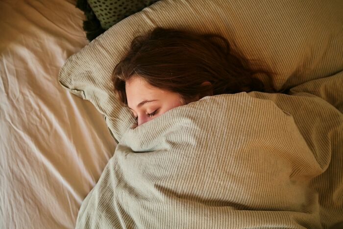 A person sleeping in bed, possibly dreaming of something creepy.
