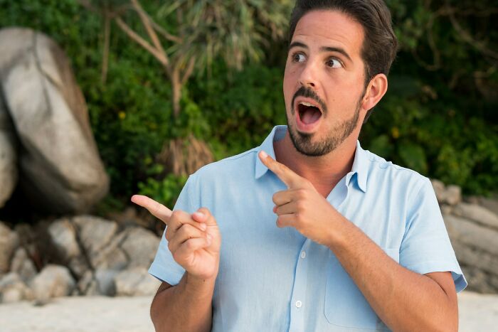 Man pointing and making surprised expression outdoors