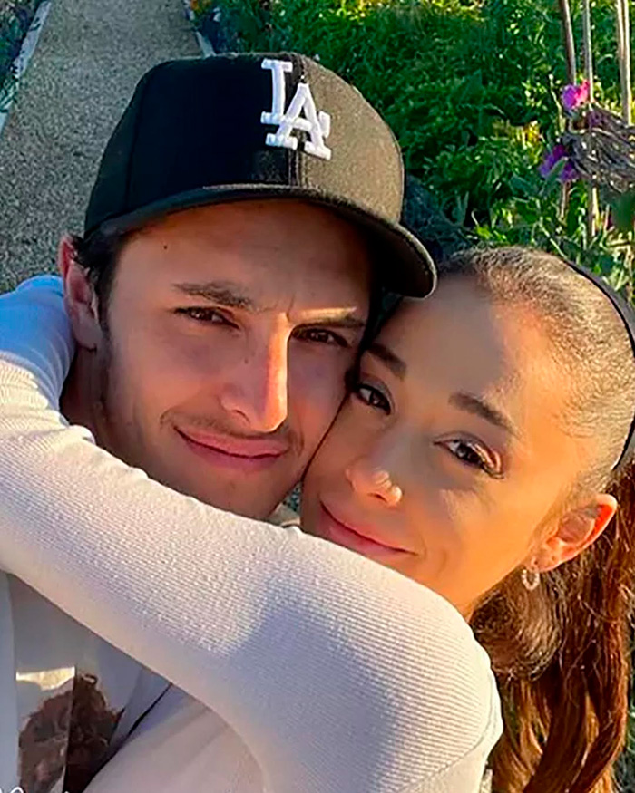 Ariana Grande hugging a man wearing an LA cap outdoors