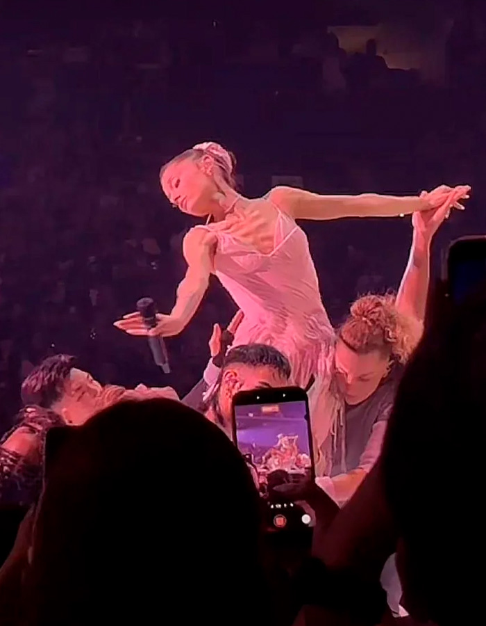 Ariana Grande wearing pink dress performing with dancers during tour