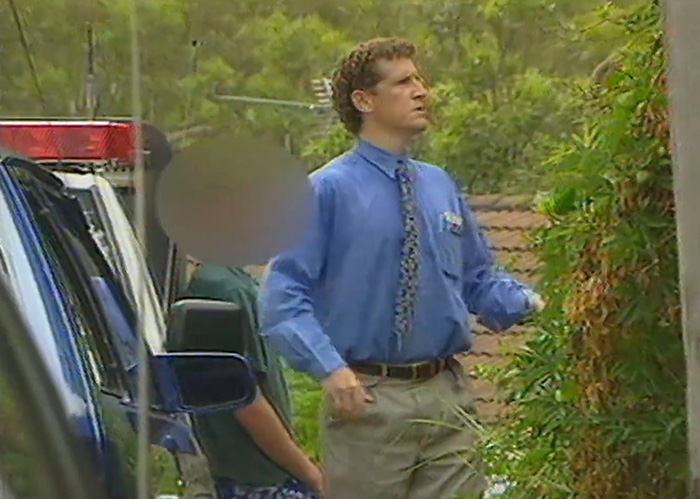 Man in blue shirt and tie near police vehicle in crime investigation