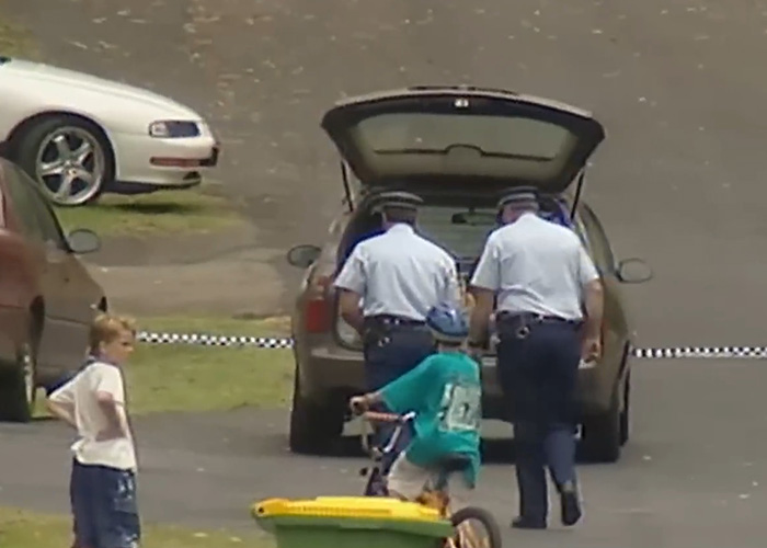 Police officers near a car in a residential area crime scene