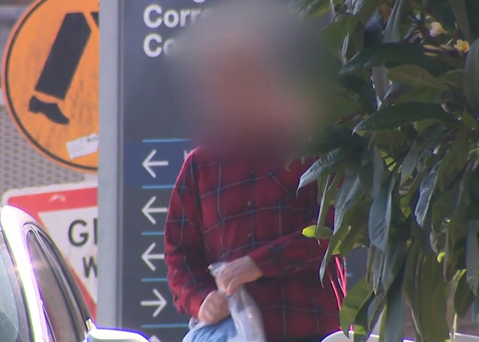 Blurred figure in red plaid near a correctional facility sign outdoors