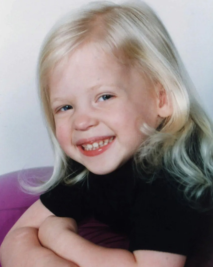 Portrait of a smiling young child with blonde hair and blue eyes