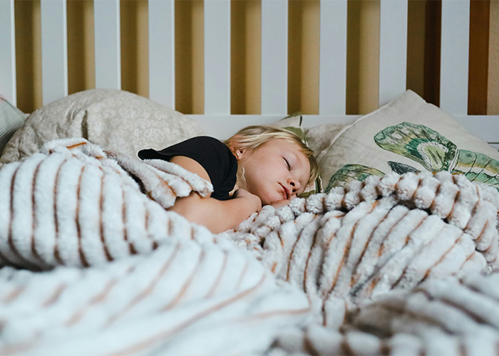 Child sleeping peacefully in bed covered with blanket