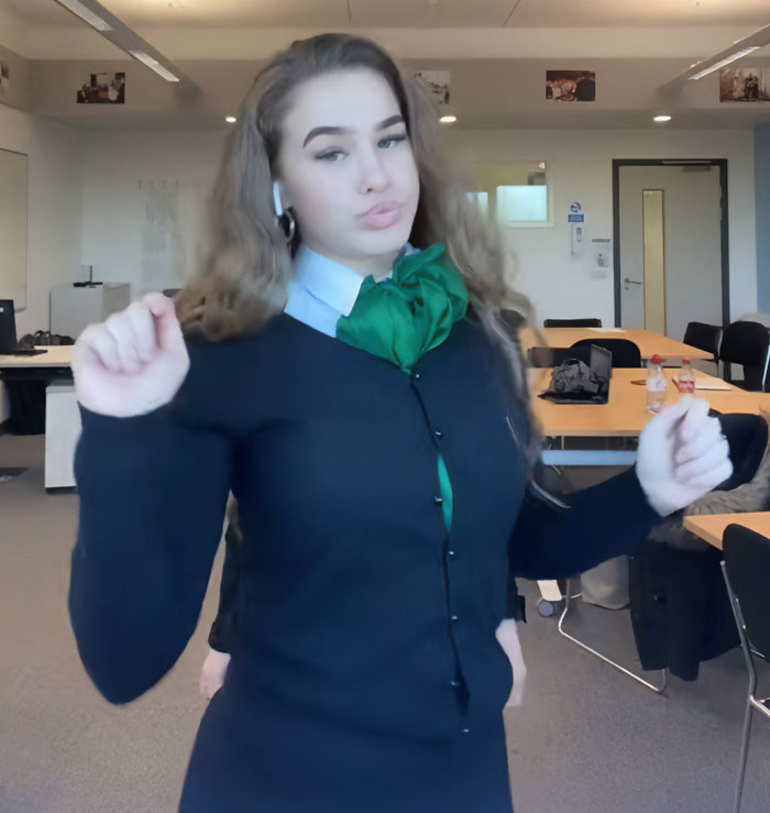 Influencer dancing in office wearing green neck scarf and black sweater