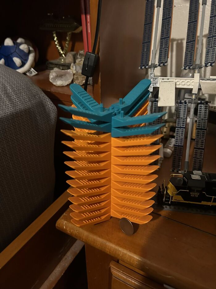 A stack of orange and teal interlocking plastic pieces, forming a bizarre, unexplained object on a table.