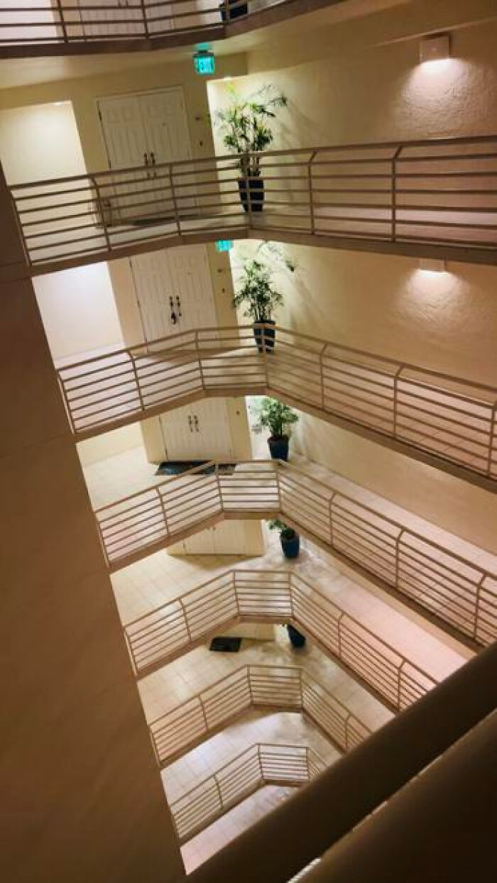 A multi-story indoor courtyard with curved balconies, an eerie haunting liminal space.