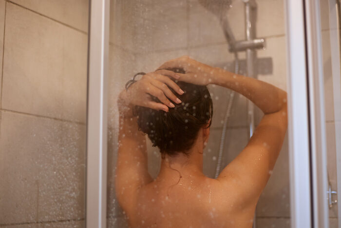 A woman showers, her back to the camera, washing her hair, depicting moments women decide to marry their partner.
