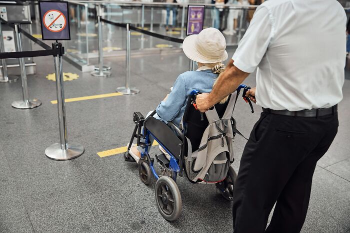 Man pushing wheelchair illustrating American healthcare and mobility support