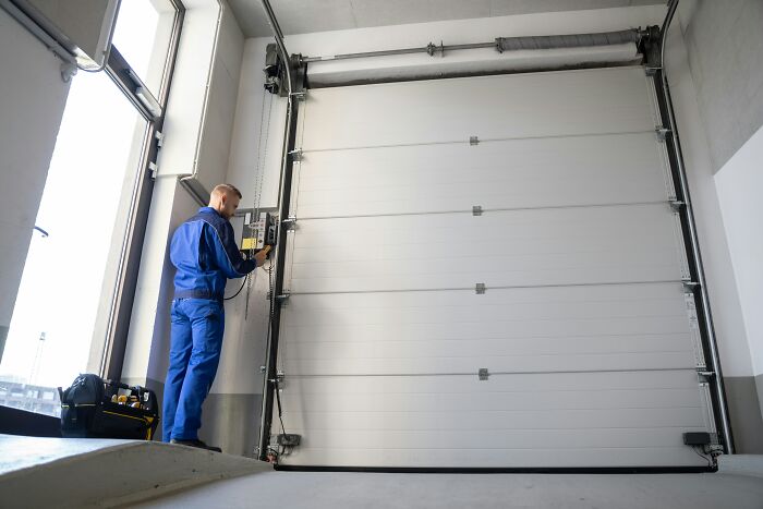 Technician repairing an automatic garage door in a modern facility