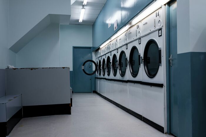 Empty laundromat with rows of washing machines and open door