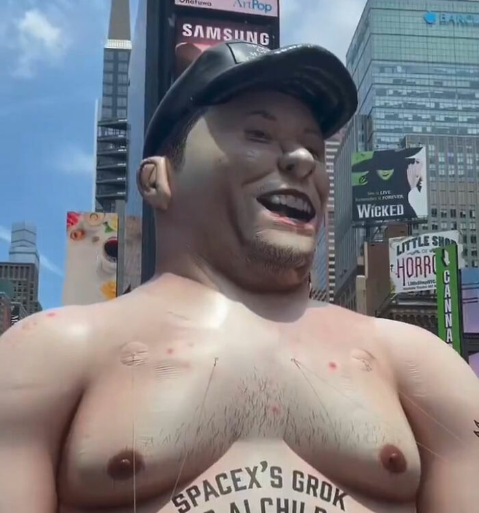 Giant inflatable of Elon Musk shirtless with cap in Times Square