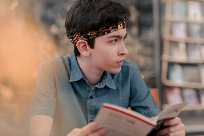 Teen boy reading a book in a library setting, illustrating Gen Alpha literacy issue