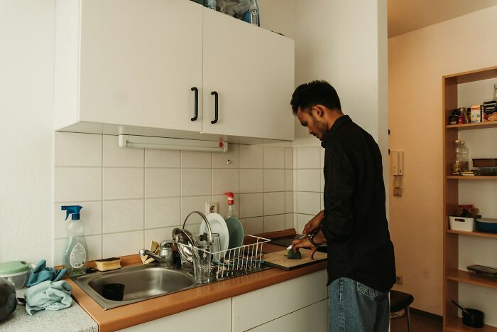 A man cooking in a small kitchen, hinting at a shocking double life.