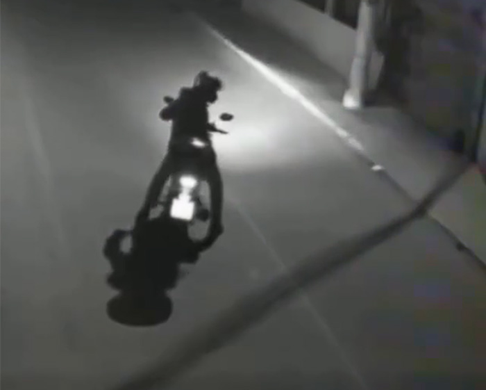 Biker at night, with headlights illuminating the dark street as he rides along.