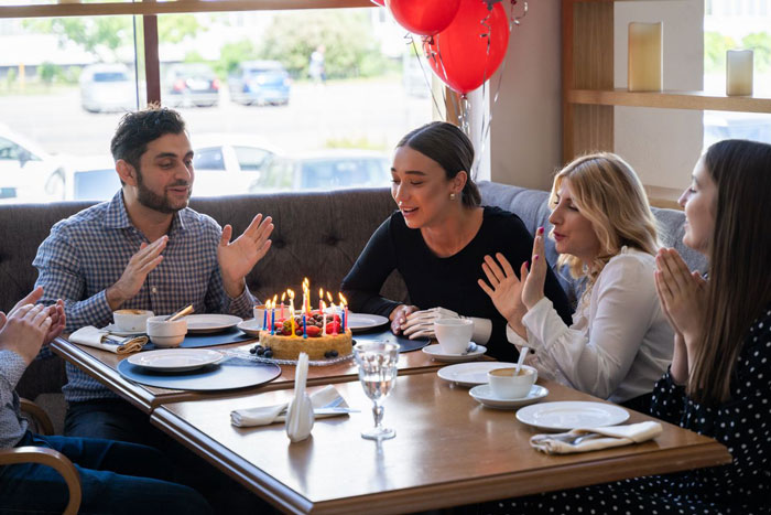 Family celebrating son's birthday with cake and balloons at a restaurant birthday party