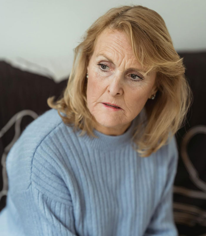 Worried older woman looking sideways wearing a blue sweater