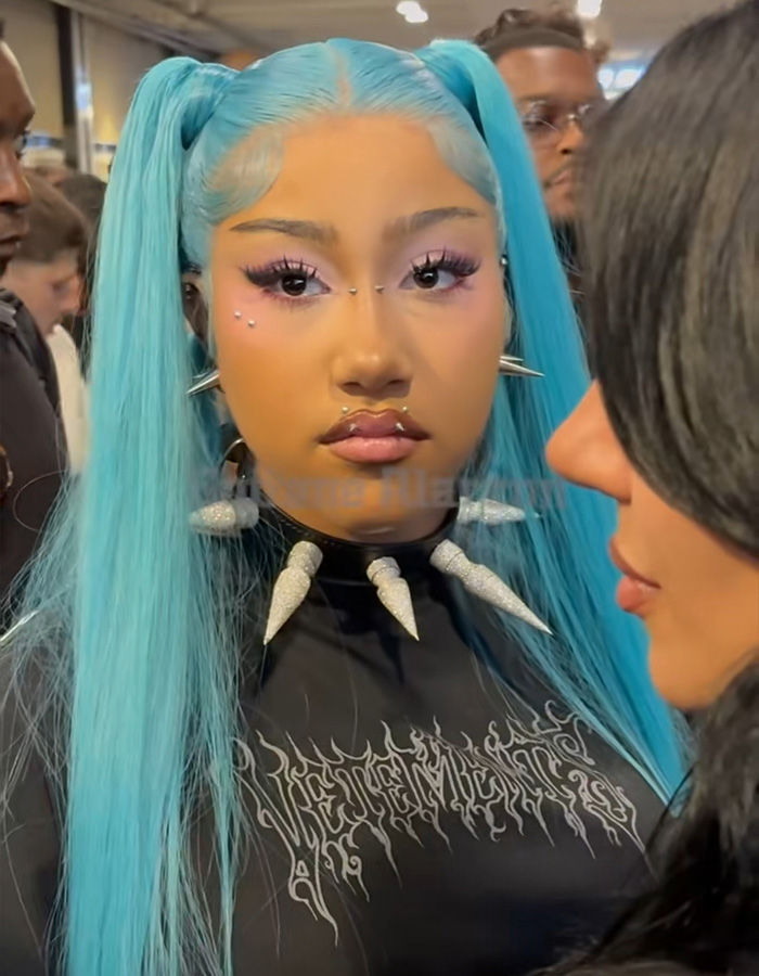 North West in blue pigtails, a black top with spikes, and unique facial piercings, highlighting parenting styles.
