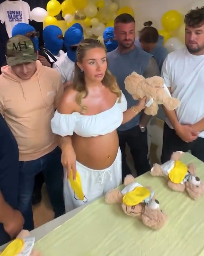 Bonnie Blue holding teddy bear surrounded by men at baby shower