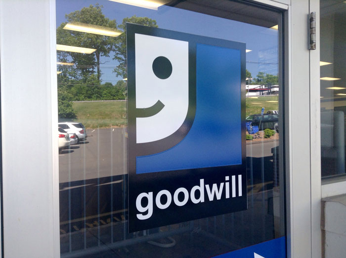 The Goodwill store logo on a glass door, reflecting the story of a customer demanding a Louis Vuitton bag.