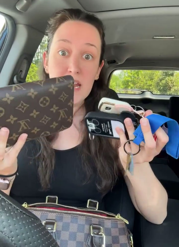 A woman holding a Louis Vuitton purse and other personal items, explaining a customer demands her bag.