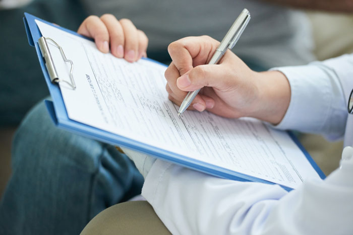 Person filling out a detailed form on clipboard Person filling out a detailed form on clipboard