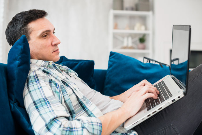 Man reclining with laptop showing obsession with data collection Man reclining with laptop showing obsession with data collection