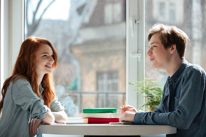 Two young people, a girl and a boy, smiling and talking, illustrating a GF's life with rules from a toxic guy.