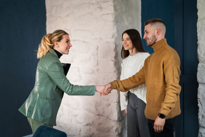 Smiling woman shaking hands with a man, while another woman watches, illustrating the outcome of a toxic guy.
